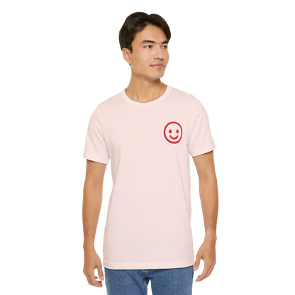 Man wearing a light pink t-shirt with a red smiley face design on a white background