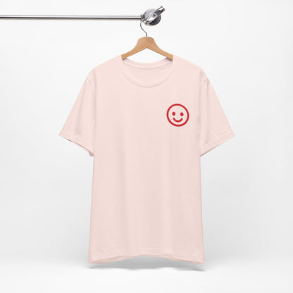 Pink t-shirt with a red smiley face on a hanger against a white background