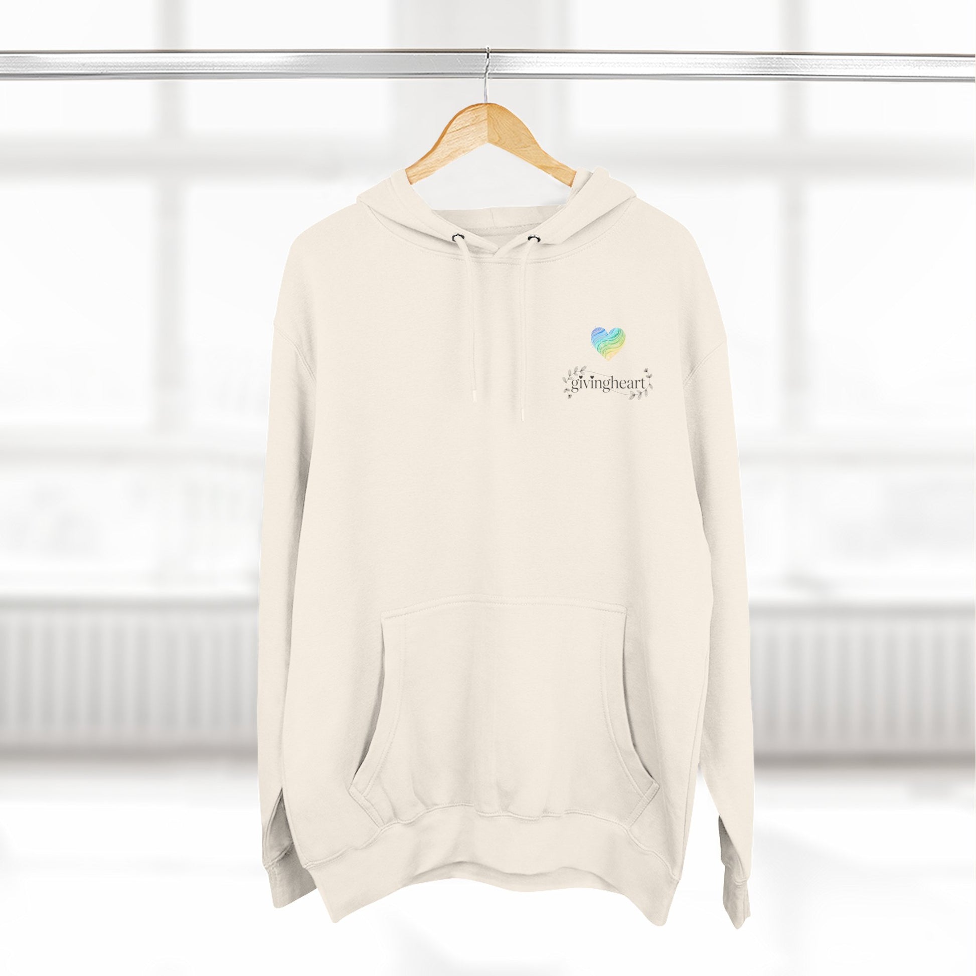 Beige hoodie with a blue/green/yellow heart logo on a hanger against a white background