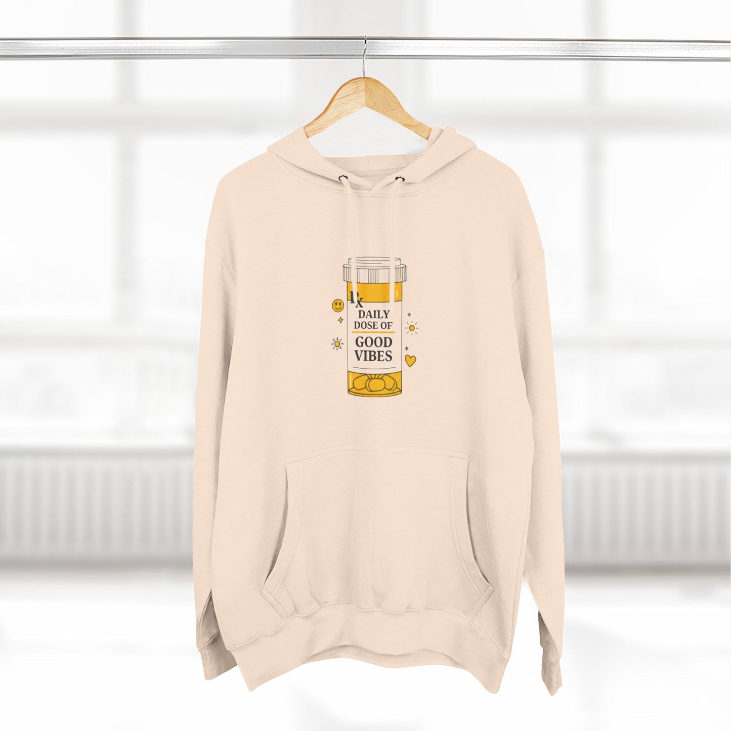 Pale pink hoodie with a daily dose of good vibes design  design on a hanger against a white background