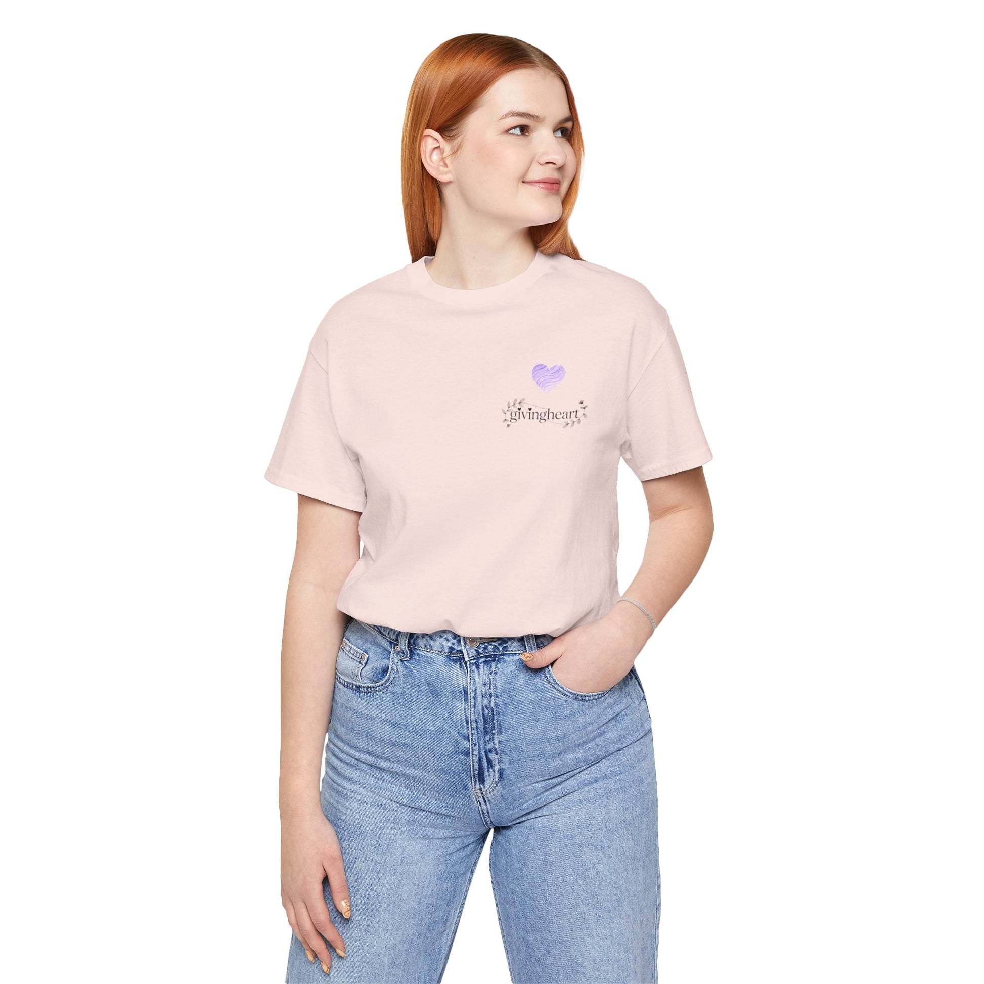 Person wearing a light pink t-shirt with a  lilac heart logo and blue jeans on a white background