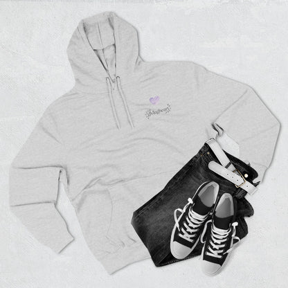 Gray hoodie with a lilac colored heart logo, black jeans, and black sneakers on a light gray background