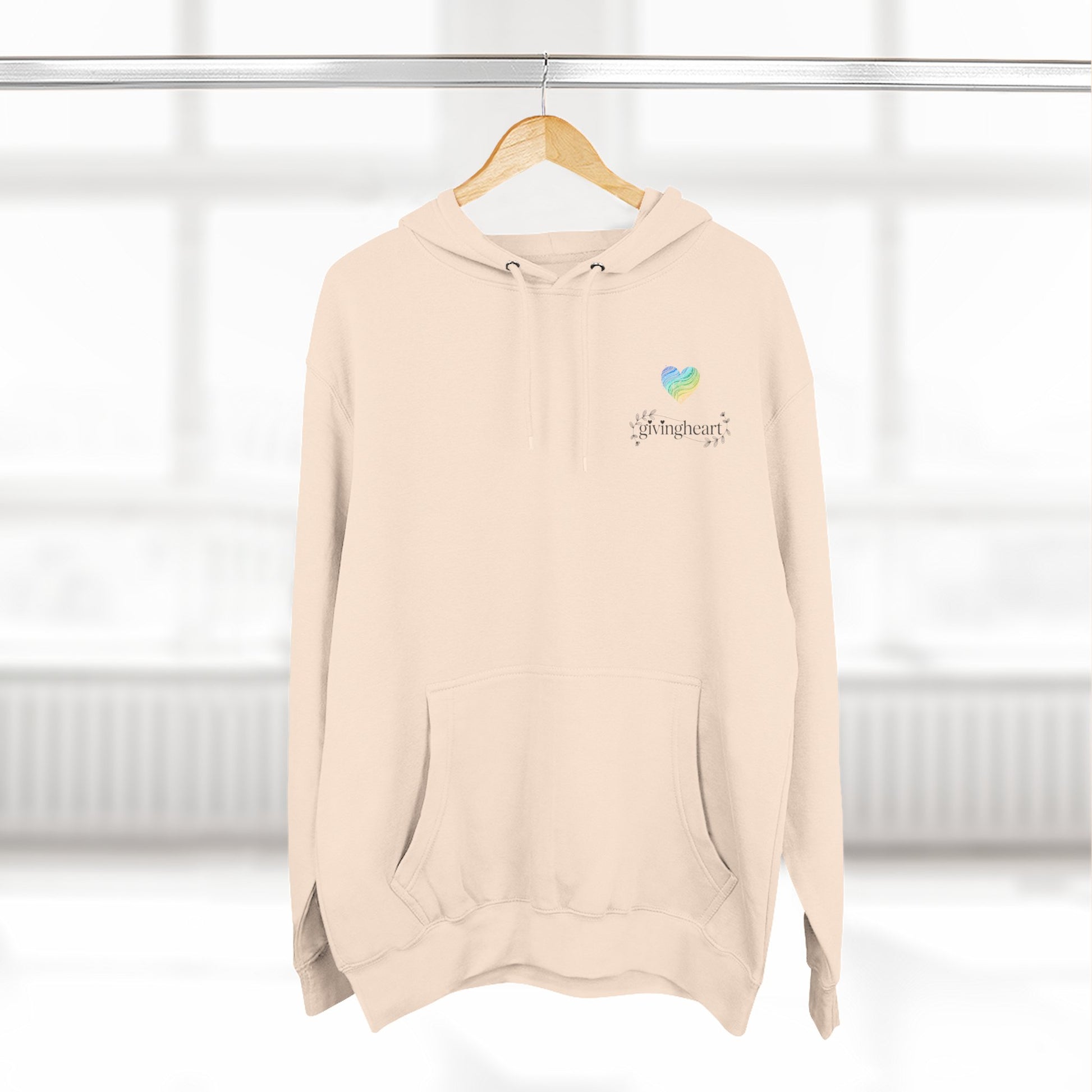 Beige hoodie with a blue/green/yellow heart logo on a hanger against a white background