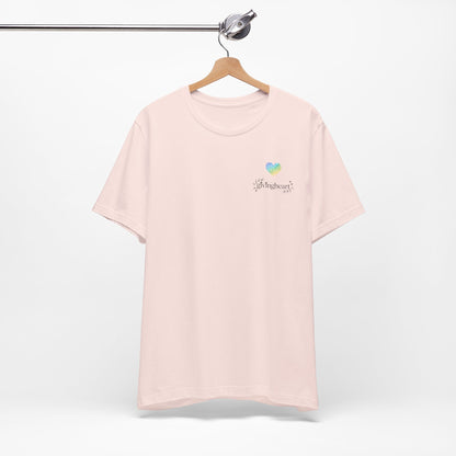 Pink t-shirt with a blue/green/yellow heart logo on a hanger against a white background