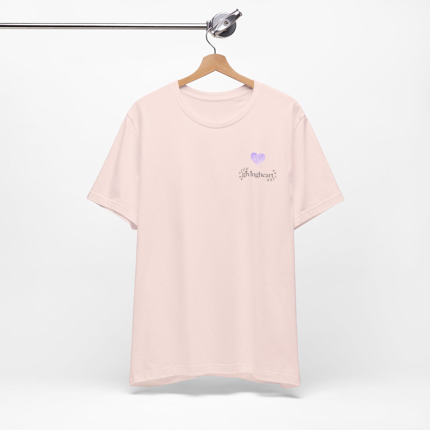Pink t-shirt with a  lilac heart logo on a hanger against a white background