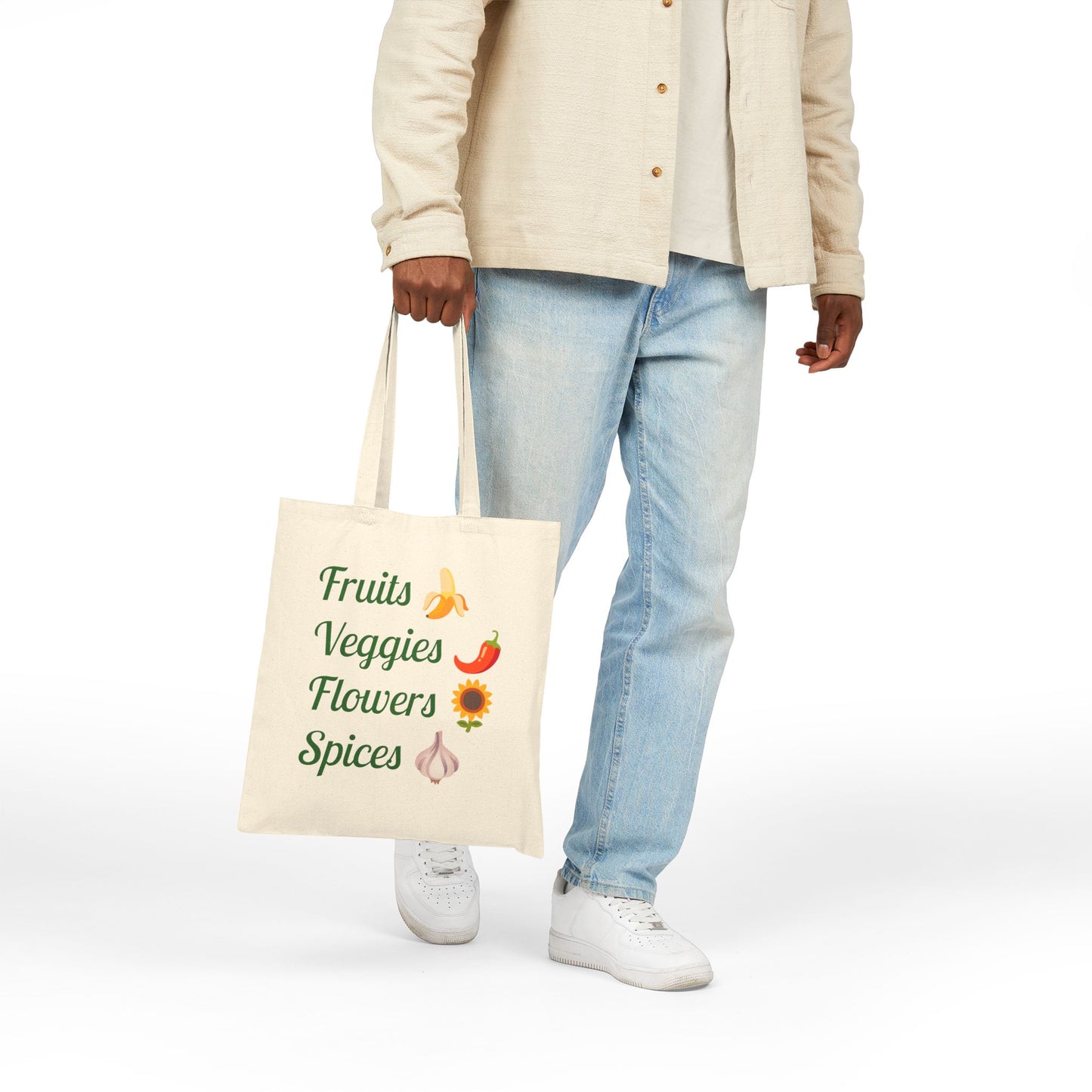 Person holding a tote bag with 'Fruits Veggies Flowers Spices' text and graphics on a white background