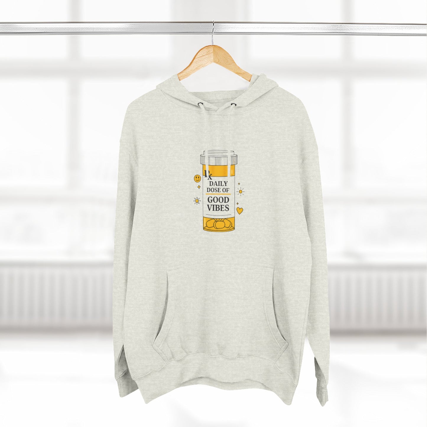 beige hoodie with a daily dose of good vibes design on a hanger against a white background
