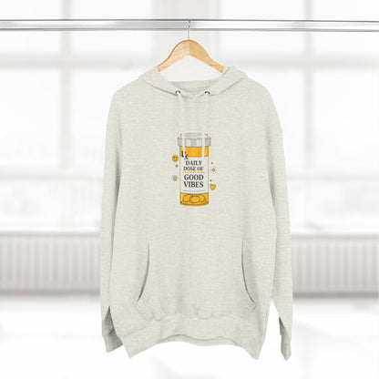 beige hoodie with a daily dose of good vibes design on a hanger against a white background