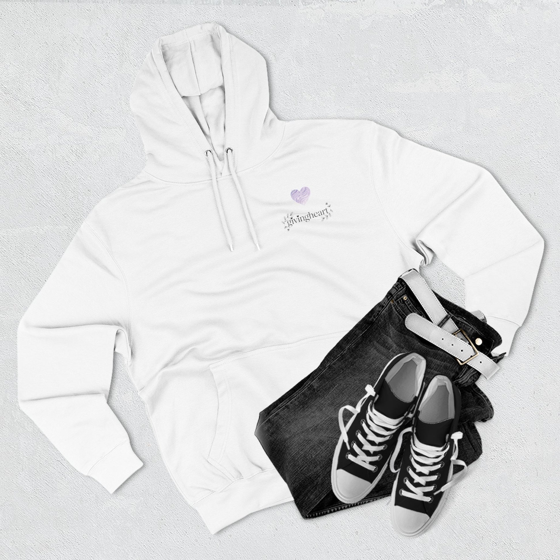 White hoodie with a lilac colored heart logo, black jeans, and black sneakers on a light gray background